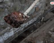 在迁安市中化煤化工有限责任公司的围墙外是污水排放沟，沟里的泥成为红褐色。